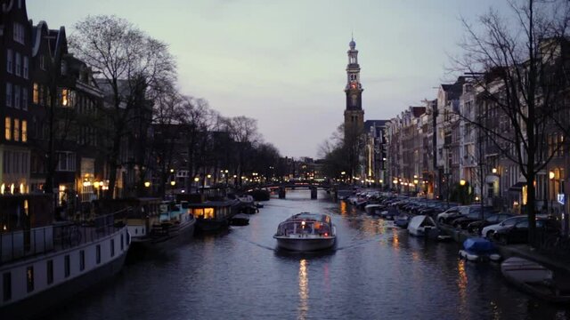 Amsterdam canal at dusk with tour boat