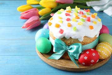 Easter cake, color eggs and tulips on blue wooden table, space for text