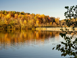 Keystone Lake in Keystone State Park in West Moreland County in the Laurel Highlands of Pennsylvania in the fall right before sunset with the fall foliage and trees reflecting in the water.