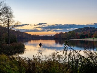 Keystone Lake in Keystone State Park in West Moreland County in the Laurel Highlands of Pennsylvania in the fall right before sunset with the fall foliage and trees reflecting in the water.