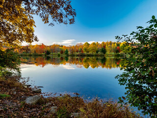 Keystone Lake in Keystone State Park in West Moreland County in the Laurel Highlands of Pennsylvania in the fall right before sunset with the fall foliage and trees reflecting in the water.