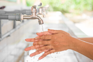 Woman washing hands from the faucet  to reduce COVID-19 infection