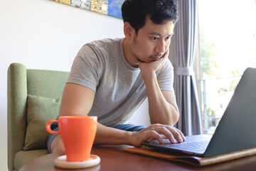 Close up of a serious Asian man working on his laptop in the coffee cafe.