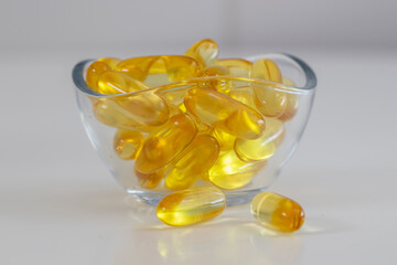 fish oil pills with omega 3 in a glass bowl on white background