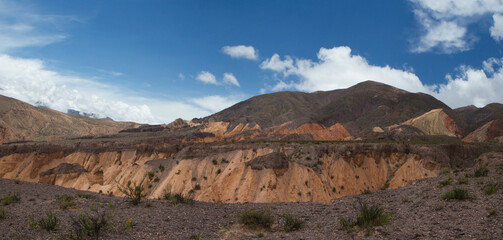High in the cordillera. Panorama view of the orange rocky cliffs, precipice and colorful mountains under a blue sky. 