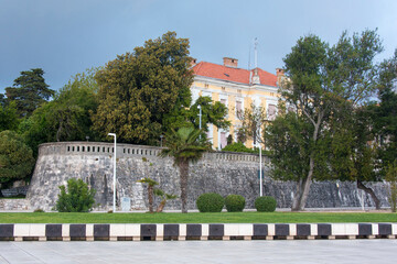 Fototapeta na wymiar Croatia, Zadar. County Government Palace and stone wall at waterfront.