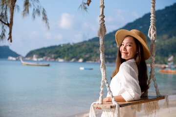Portrait image of a beautiful young asian woman with swing by the sea