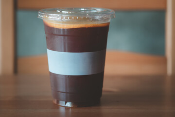Black iced coffee topping with sliced orange on wooden background.