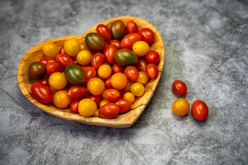 Cherry tomatoes in a wooden heart-shaped plate. 