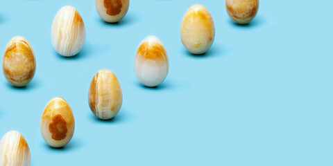 Pattern from Easter eggs from Natural gemstone onyx on blue paper. Trendy spring holiday arrangement.