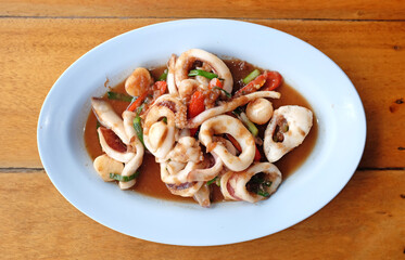 Stir fried squid with shrimp paste on plate on table background.