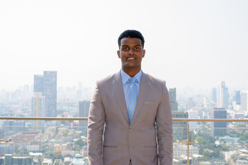 Portrait of handsome young African businessman wearing suit while smiling