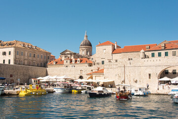 Tour boats outside walled city. Crowds depart through western gate.