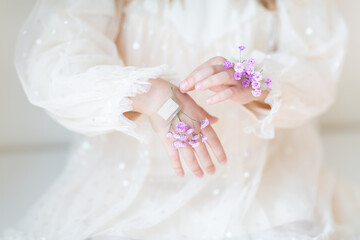 Close-up portrait of smiling little caucasian girl with gypsophila flowers isolated on grey background. Model in studio. Trendy creative idea