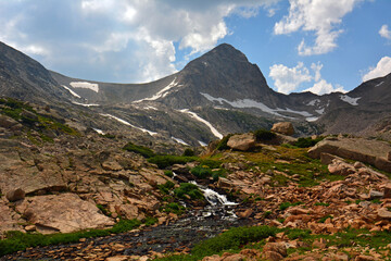 magnificent arapahoe, navajo, and shoshoni peaks with a mountain stream and snowfield on a sunny...