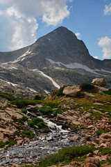 magnificent arapahoe, navajo, and shoshoni peaks with a mountain stream and snowfield on a sunny summer day along the lake isabele trail in the indian peaks wilderness area near nederland, colorado