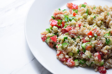 Healthy quinoa salad with fresh vegetables on a white plate