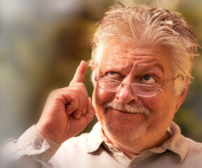 an older man with glasses has an idea, he symbolically lifts a finger