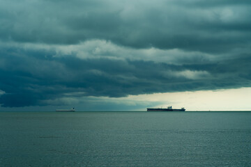 Seaview with ships in Port Dickson. Heavy clouds in rainy season. The image contain soft focus, noise and grain.
