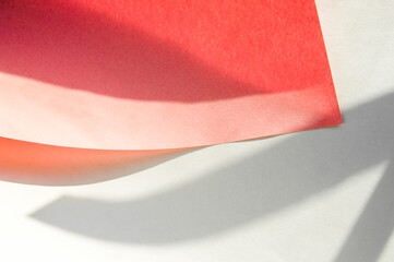 Obraz premium Layout sheet of paper of red color curved on a white background. Creative paper mockup with shadow overlay effect with geometric pattern