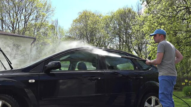 man spray wash car with high water pressure washer outdoor. 4K