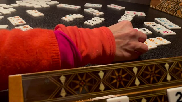 Woman's Hand Playing Rummikub Board Game On The Table. dolly-in shot