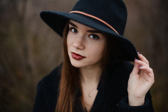 Beautiful woman in hat posing during gloomy autumn day
