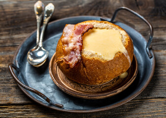 Cheese soup with bacon and herbs served in bread on wooden background, Restaurant menu, dieting, cookbook recipe