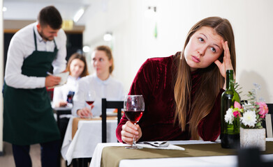 Sad woman is dining in luxury restaurante alone indoor.