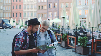 Fototapeta premium Young man and woman looking on main tourist attractions using map. They are so happy to go sightseeing.