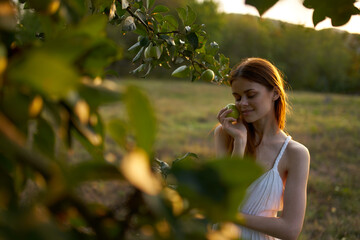 woman near the apple tree in a white dress outdoors in the garden