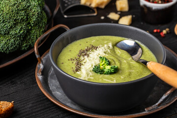 bowl of broccoli cream soup with parmesan cheese and crunchy croutons on wooden table, top view