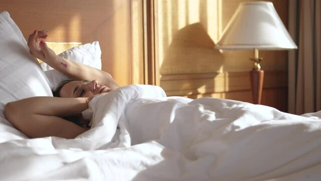 Calm young woman goes to sleep in comfortable cozy fresh bed enjoying healthy good sleep nap. slow motion
