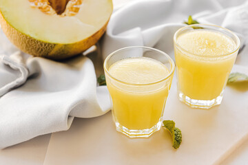 Glasses with melon smoothie on light background