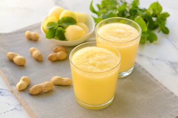 Glasses with melon smoothie and peanuts on light background