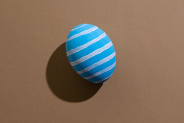 Easter symbol. Festive gift card. Holiday decoration. Abstract background. Blue egg with white lines ornament pattern isolated on beige copy space.
