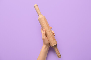 Female hand with rolling pin on color background