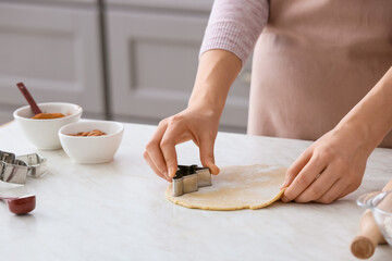 Woman making cookies on table in kitchen