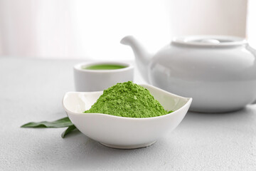 Bowl with powdered matcha tea, teapot and cup on table