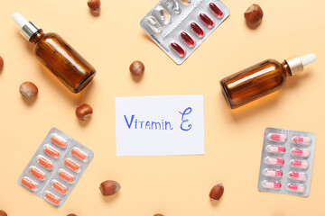 Text VITAMIN E with healthy nuts, pills and oil on color background