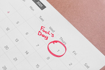 Calendar with marked date of April Fool's Day on color background, closeup