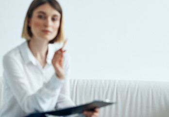 a woman in a shirt with documents in her hands sits on a sofa indoors