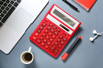 Modern calculator with laptop and stationery on grey background