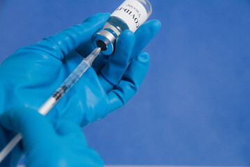 Hands in blue medical gloves drawing a syringe with covid-19 vaccine from a vial