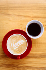 Coffee in a red cup with milk and latte art and coffee in a white cup on a table
