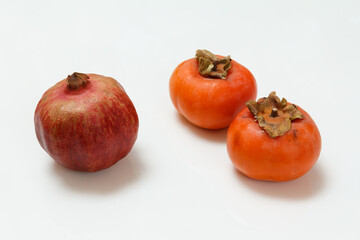 Ripe fresh pomegranate and persimmon fruits on white.