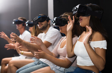 Excited woman is experiencing with friends virtual reality in entertainment room.