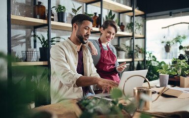 Shop assistants with laptop working in potted plant store, small business concept. - Powered by Adobe