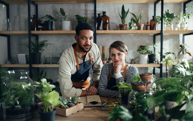 Shop assistants looking at camera in indoor potted plant store, small business concept.