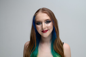 Portrait on a white background of a caucasian brunette model with long dyed hair and bright makeup